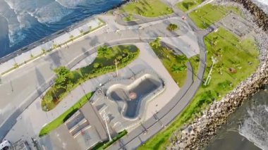 Sahilde dalgalı bir yol ve küçük bir park arasındaki spor sahasının en üst görüntüsü.