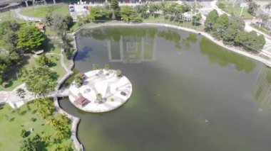 Top Aerial View Of Green Lake With Reflections Near Buildings And Roundabouts - Static Converted