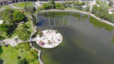 Top Aerial View Of Green Lake With Roundabouts And Reflections Of Buildings Near The Park - Dolly Right To Left.
