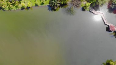 Top View Of Lake With A Small Bridge Between A Green Park - Moving Up