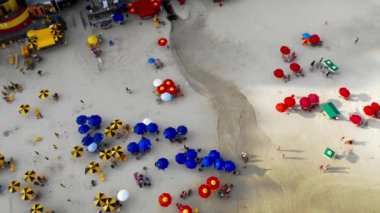 Sahilde güneşlenen ve oynayan bir sürü renkli şemsiyeyi ve insanların en iyi görüntüsü. 