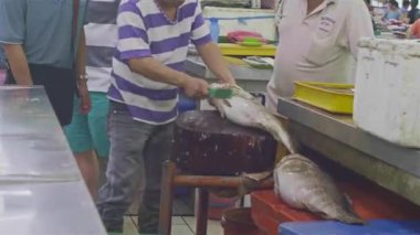  Bir adam büyük bir balığı temizliyor.