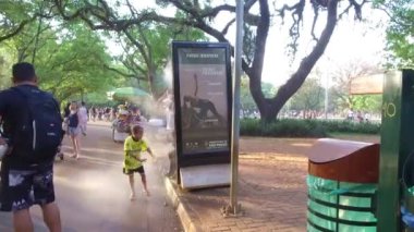 Beyaz gömlekli büyükbaba su püskürtücüsüyle oynuyor.