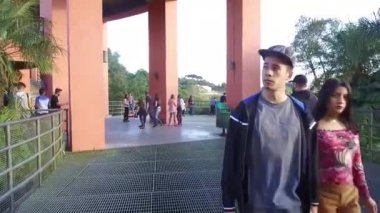 Siyah ceketli ve şapkalı adamlar güzel doğal manzaralı binalarda yürüyorlar.