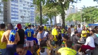 Brezilyalı hayranlar tarafından doldurulmuş bir kafede yemek yiyen mavi gömlekli kadınlar.