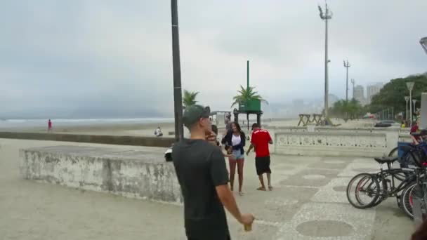 Pessoas Estão Apoiando Rocha Perto Praia Com Uma Vista Cidade — Vídeo de Stock