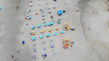 Beyaz kumlu bir sahilde çadırların ve şemsiyelerin üst hava manzarası..