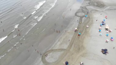 Beyaz kumlu bir plajda çadırların ve şemsiyelerin üst hava manzarası - ön doli