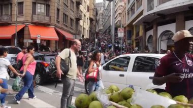 Uzun kahverengi binalar arasında bir sürü insan ve satıcı var.