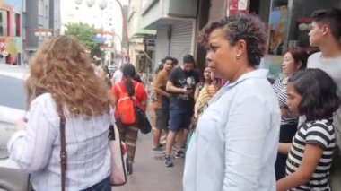 Dükkânın önündeki kaldırımda bir sürü insan var.