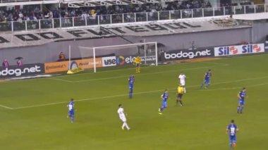 Beyazlı adam futbol maçında futbol topunu tekmeliyor.