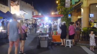  Melaka Jonker Caddesi 'ndeki gece pazarındaki yemek standları ve aksesuarların arasındaki ziyaretçiler