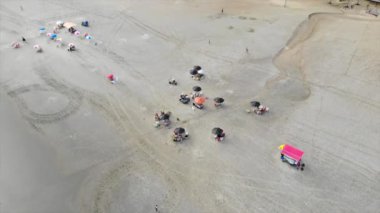 Brezilya 'da kumlu bir plajda siyah şemsiyeli insanların üst hava manzarası..