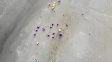 Brezilya 'da kumlu bir plajda insanların üstten görünüşü ve şemsiyeler.