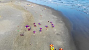 Şemsiyeli, kumlu bir plajın üst manzarası.