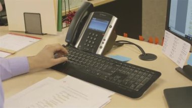 Ofisteki masaüstü bilgisayarında çalışan mavi gömlekli adam.