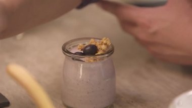 blueberry being put on top of yogurt - static