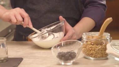 Hand mixing the yogurt inside glass bowl - slide left.