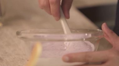 Hand mixing with white spatula in bowl - static