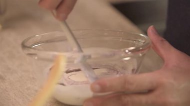Close up of hand mixing yogurt in glass bowl - static