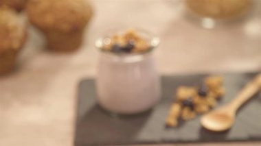 Jar of yogurt with garnish and wooden spoon at the side - rack focus