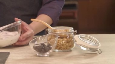 man mixing yogurt on the table with jars - slide left.