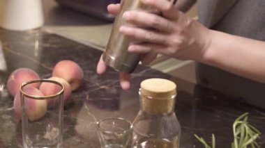 Adam daha büyük bardağa içki doldurup sallıyor. 