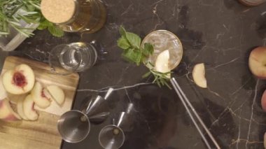 Adam içkinin üstüne şeftali dilimleri koyuyor.