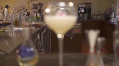 a glass drink with flowers next to jigger - rack focus.