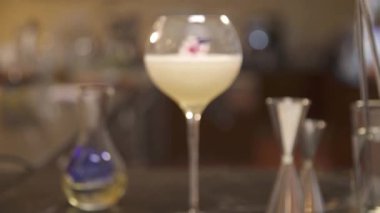 a glass drink with flowers next to jigger - static rack focus
