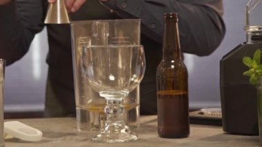 Eller cam şişeyi alır, üstünde de jigger vardır. 