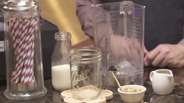 手拿起玻璃瓶旁边的搅拌机 — 图库视频影像