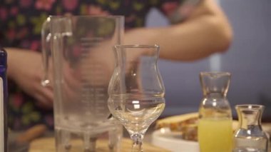 Barista masaya bir şişenin yanına jigger koyuyor.