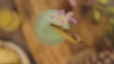 Flower petal on top of drink with pineapple slice - rack focus