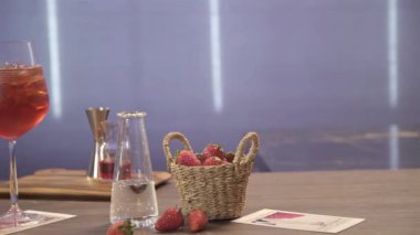 Bardak altlığında çilek olan kırmızı bir içecek.