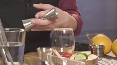 Jigger 'dan bardağa şeffaf bir şurup dökülüyor.