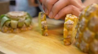 Güvertede ananas doğrayan bir kadın var.