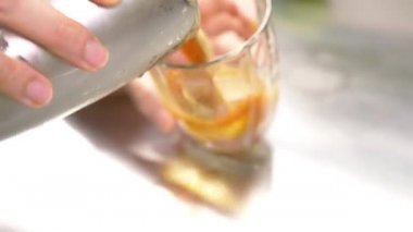 Kadın cam bardağa kahve dolduruyor.