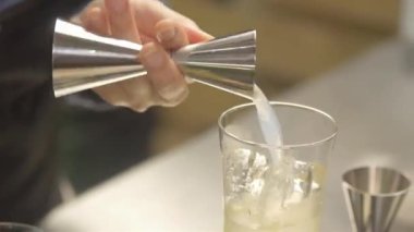 Kadın jiggerdan cama beyaz şurup döküyor.