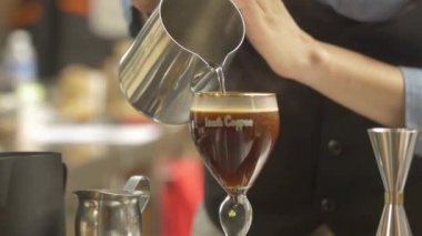 Kadın sıcak bardağa su döküp karıştırıyor.