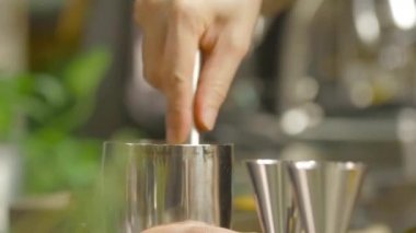 Gümüş karıştırıcı bardağın içinde küçük bir çekiç büken kadın.