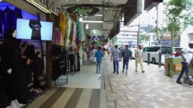 Dükkanların yanında yürüyen bir grup insan.