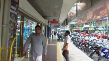 İnsanlar dükkan ve motor arasında yürürler..