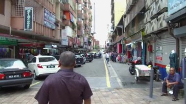  İnsanlar dükkanların önünden geçerken sıra sıra park etmiş arabalar.