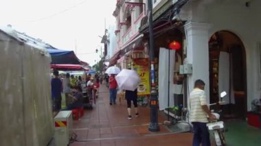 İnsanlar tezgahın yanında yürürken şemsiye tutuyorlar..