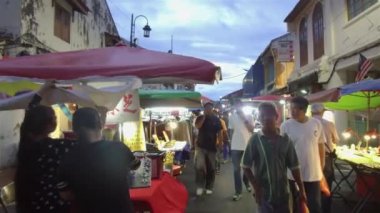İnsanlar karanlık gökyüzüyle tezgahın etrafına bakıyorlar.