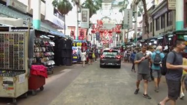 İnsanlar yürürken araba yoldan geçiyor.