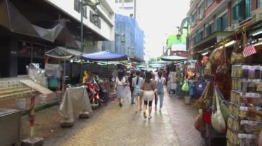  İnsanlar sokakta tezgahların yanında yürüyorlar.