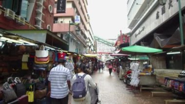Sıralar dolusu tezgah çanta satıyor ve insanlar yürüyor.