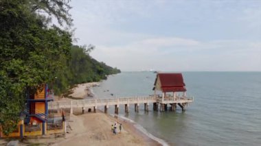 Sahildeki bir rıhtımın sonundaki kırmızı çatı kulübesi..